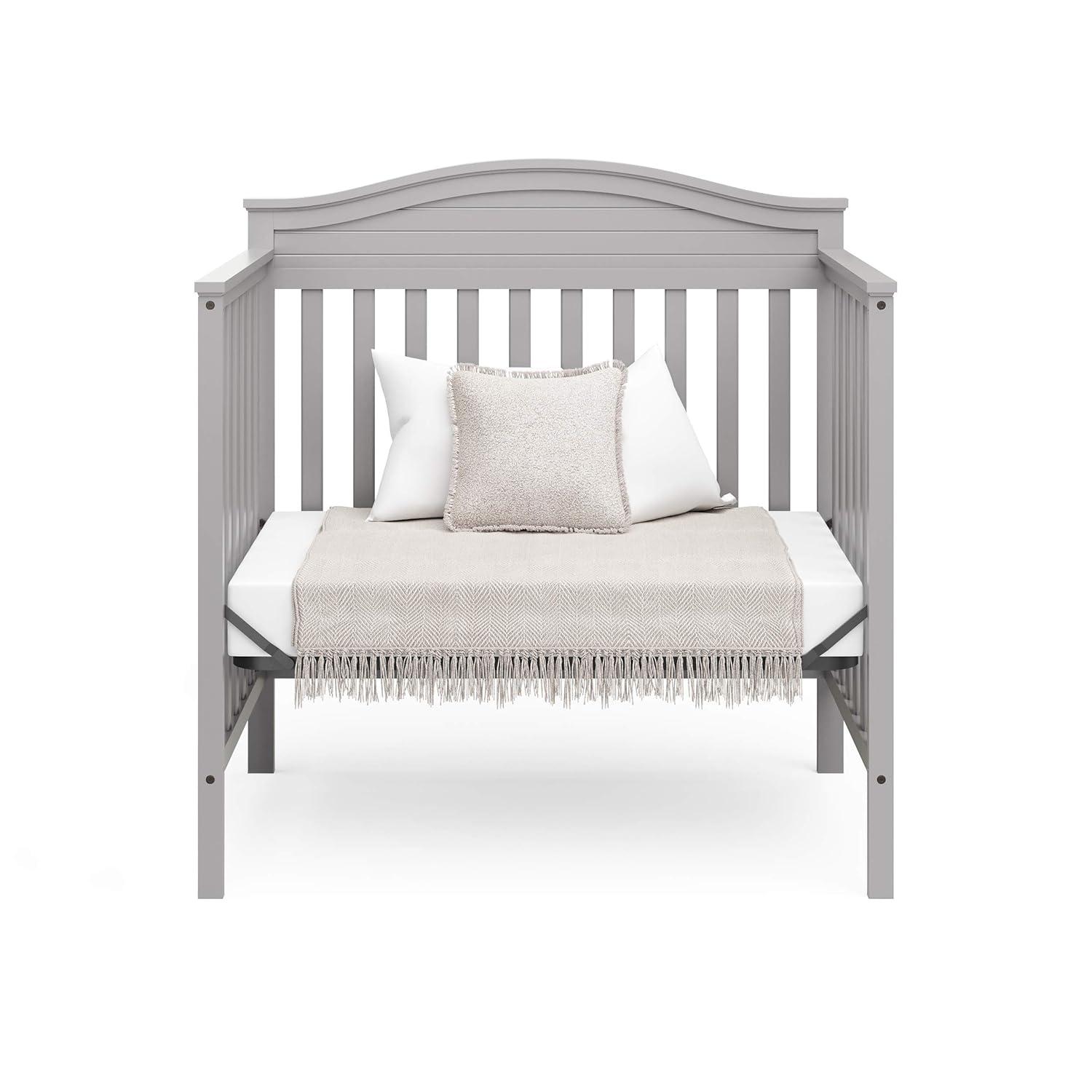 imageGraco Stella 4in1 Convertible Mini Crib with Bonus Mattress Pebble Gray Includes Bonus 275 Inch Thick Mattress with WaterResistant Cover Converts to Twin Bed Ideal Crib for Small SpacesPebble Gray